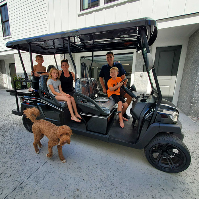 A Family of five enjoying their brand new Bintelli A 6 seater street legal golf cart in black parked on their driveway