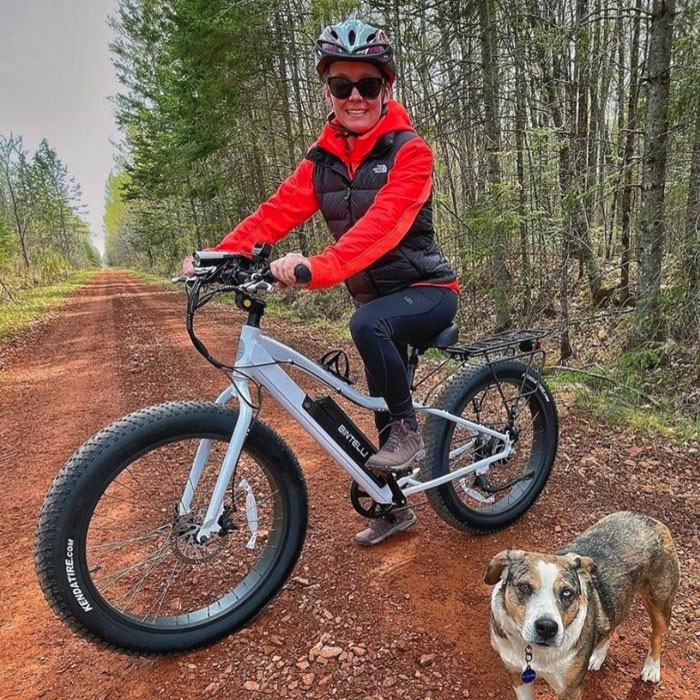 Man rides bintelli electric white bike next to a dog.
