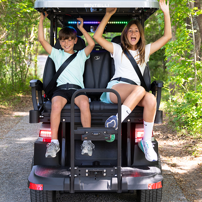 kids on the back of a bintelli golf cart