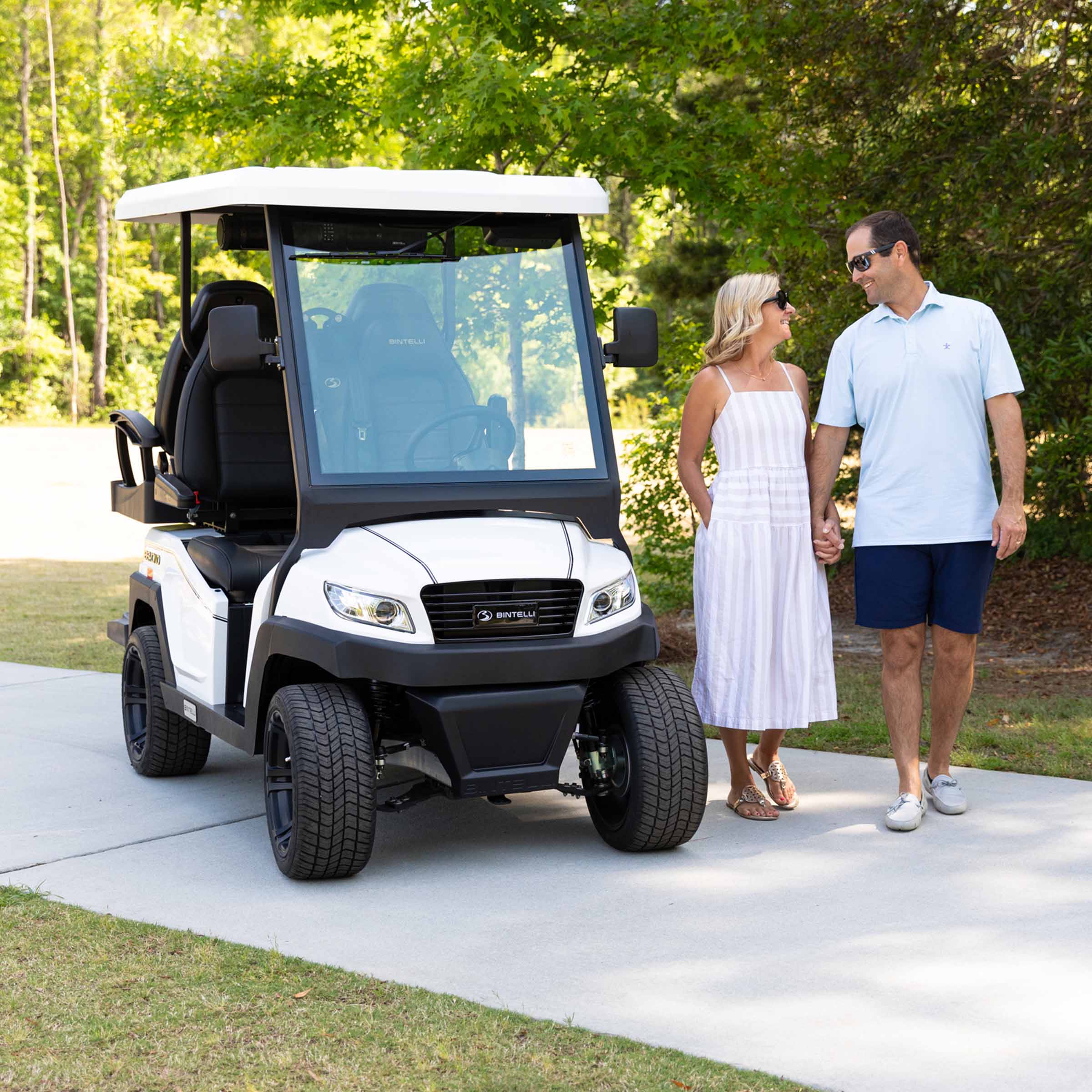 couple standing next to there bintelli beyond golf cart